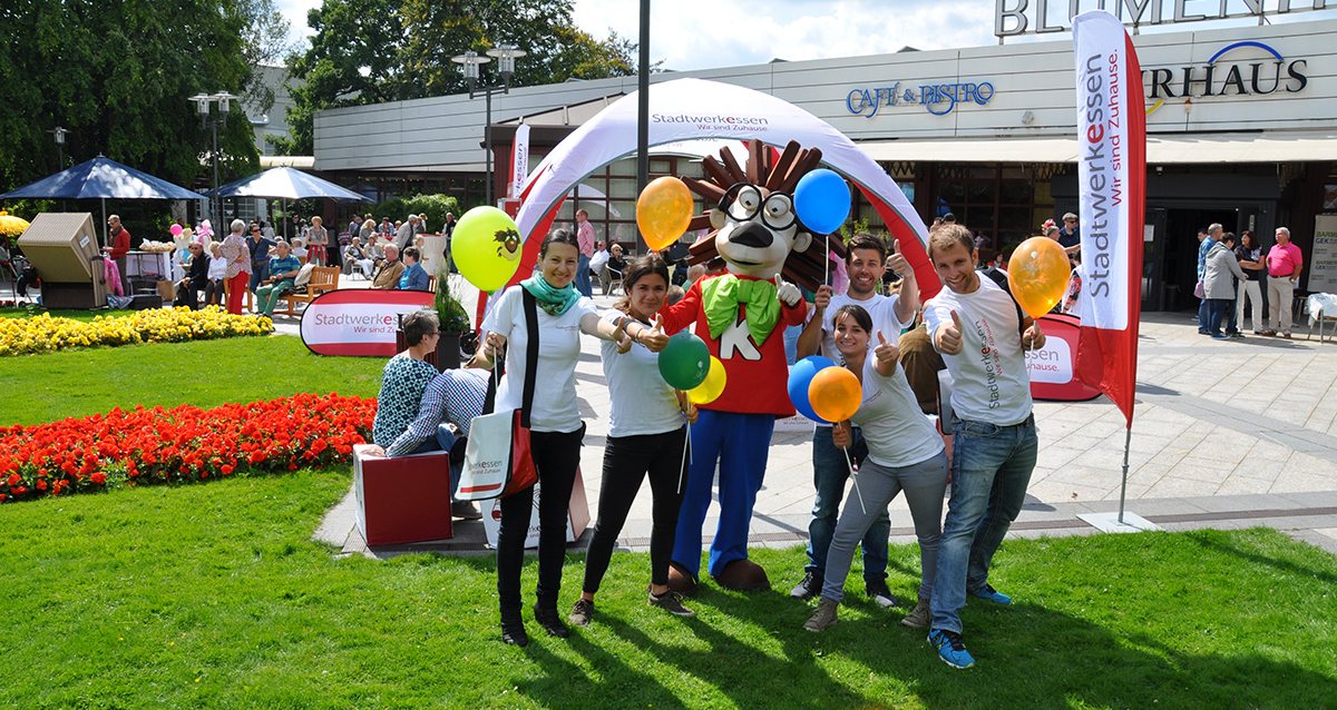 Promotion-Team mit Maskottchen an einem Aktionsstand